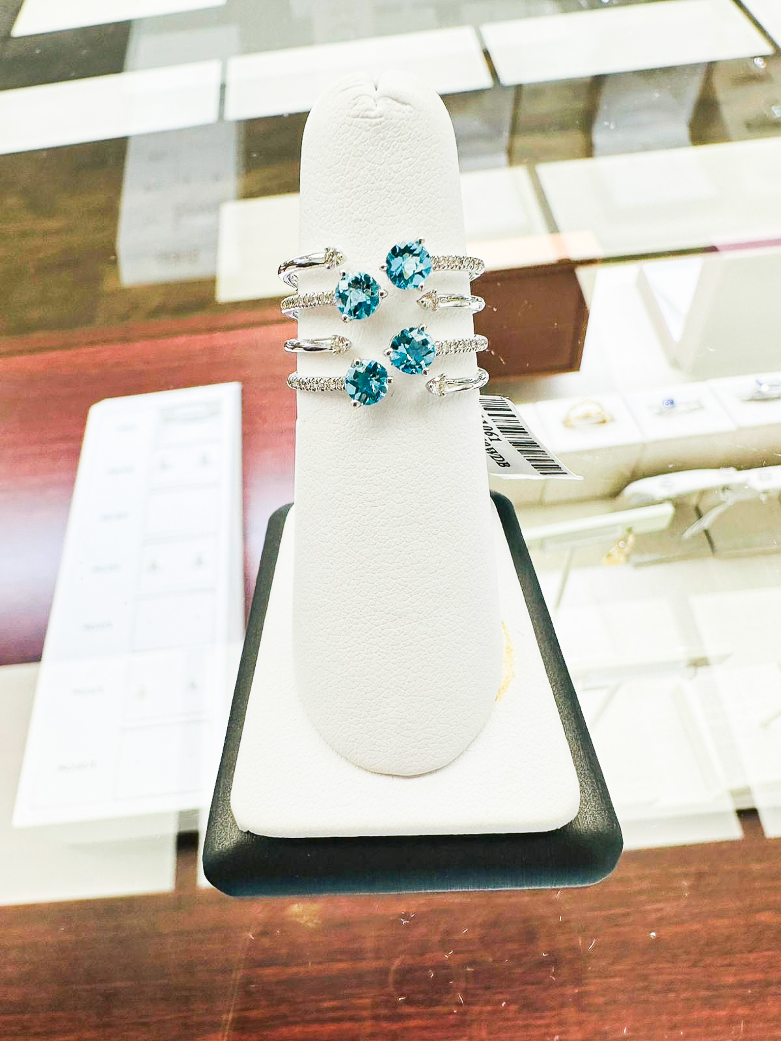 Four stunning blue gemstone rings with diamond accents displayed on white ring stand